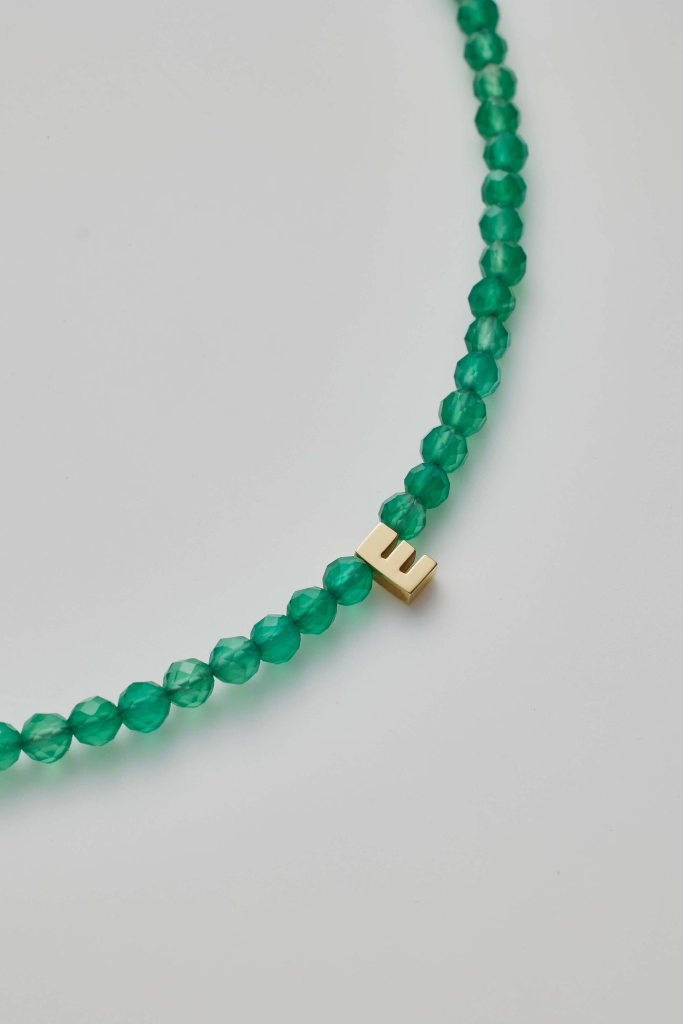 Green onyx gemstone bracelet with a gold letter charm.