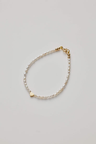 Delicate bracelet with lustrous pearls and a gold heart charm, elegantly crafted.