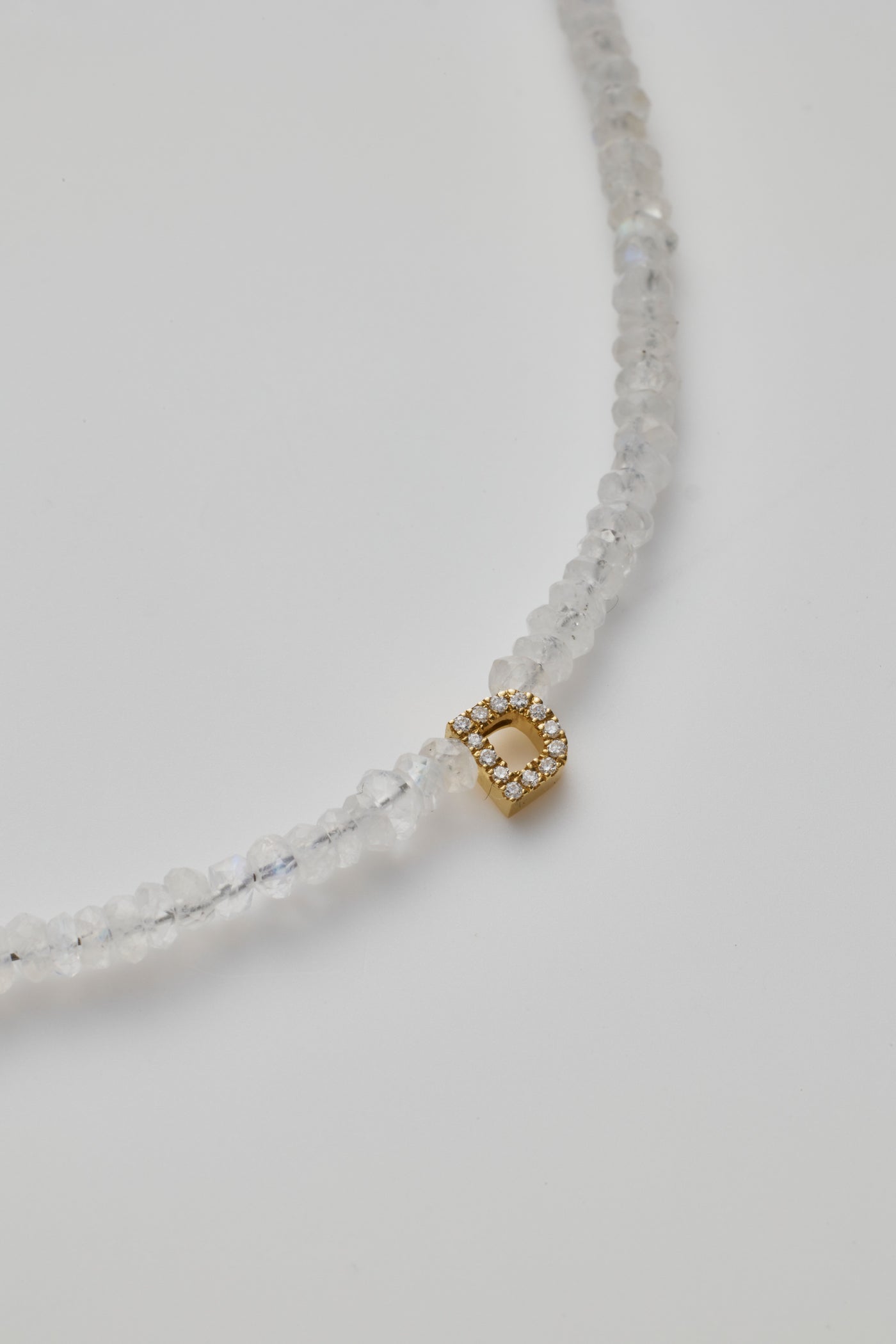 Delicate bracelet with moonstone beads and a diamond alphabet charm, elegantly crafted.