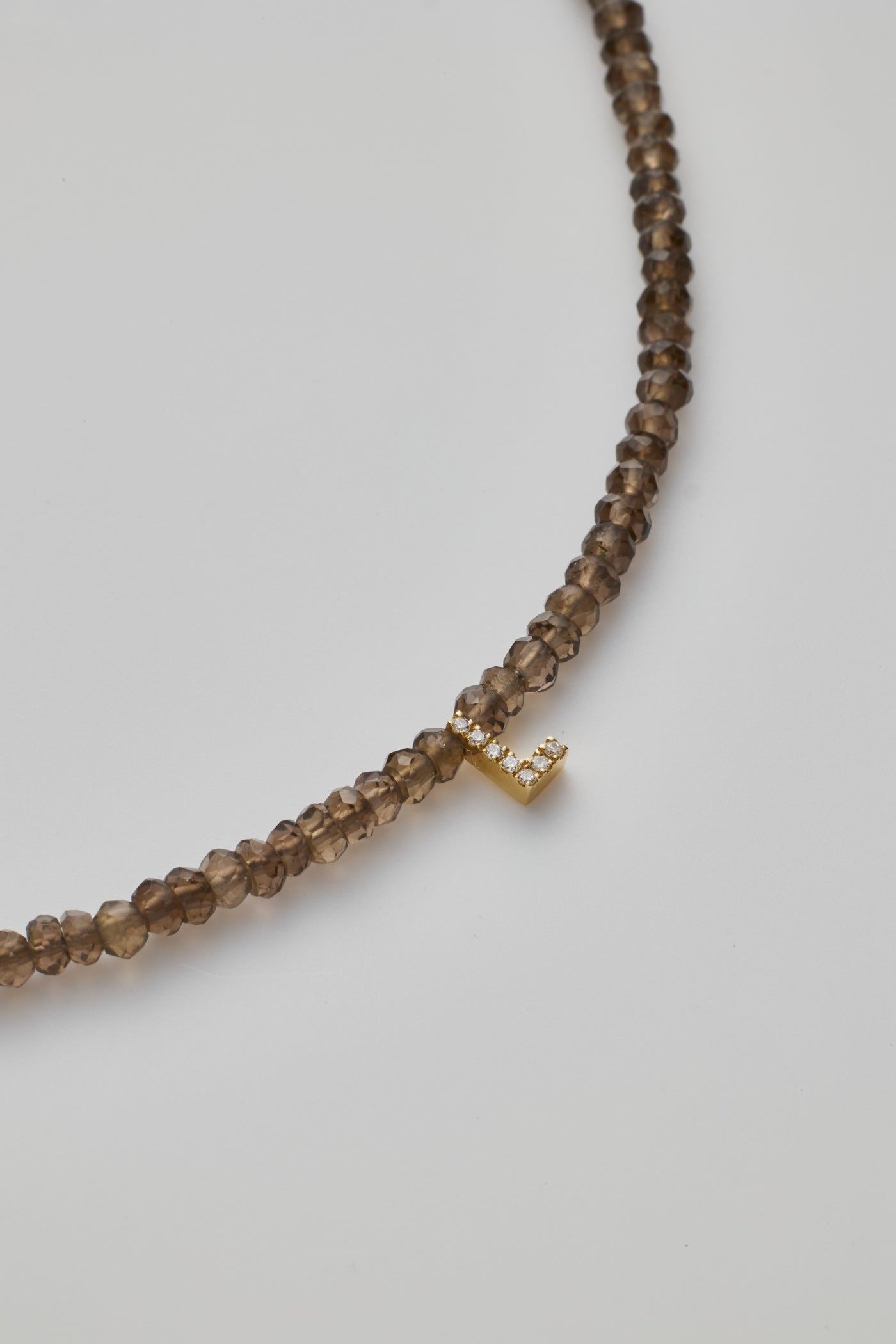 Delicate bracelet with smoky quartz  beads and a diamond alphabet charm, elegantly crafted.