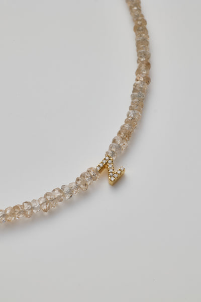 Delicate bracelet with natural zircon beads and a diamond alphabet charm, elegantly crafted.