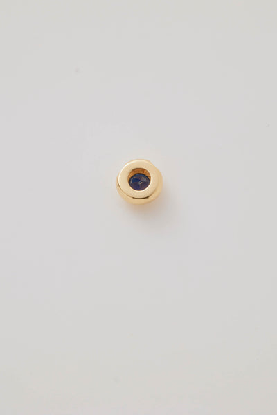 The reverse side view of the September Birthstone Charm featuring a deep blue sapphire gemstone in an elegant gold setting. Photographed on a light grey background.