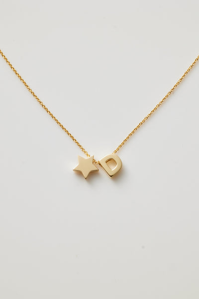 The One Letter and Star Necklace in 18k Gold features a delicate gold chain with two charms: a capital letter 'D' and a small star. Both charms, crafted from 18k solid gold, hang elegantly close together in the centre against a plain white background, highlighting the necklace's refined beauty.