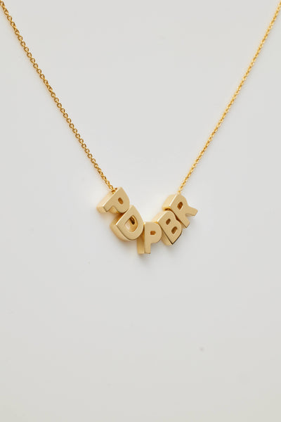 The Five Letters Necklace in 18k Gold is a delicate chain necklace adorned with five solid gold letters - PDPBR hanging gracefully at the centre. These evenly spaced letters form an abstract or acronymic design that stands out beautifully against a white background.