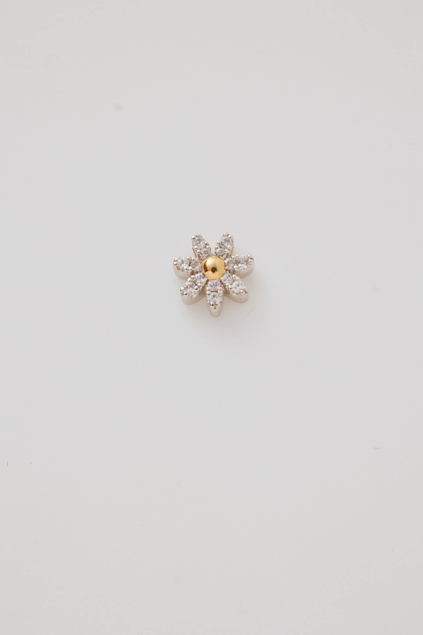 A sparkling diamond daisy charm featuring a radiant centre stone and petal-like diamonds. Elegantly photographed on a light grey background.