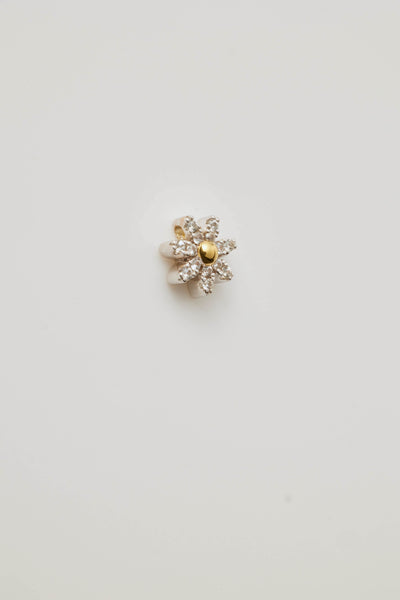 Side view profile of a sparkling diamond daisy charm featuring a radiant centre stone and petal-like diamonds. Elegantly photographed on a light grey background.