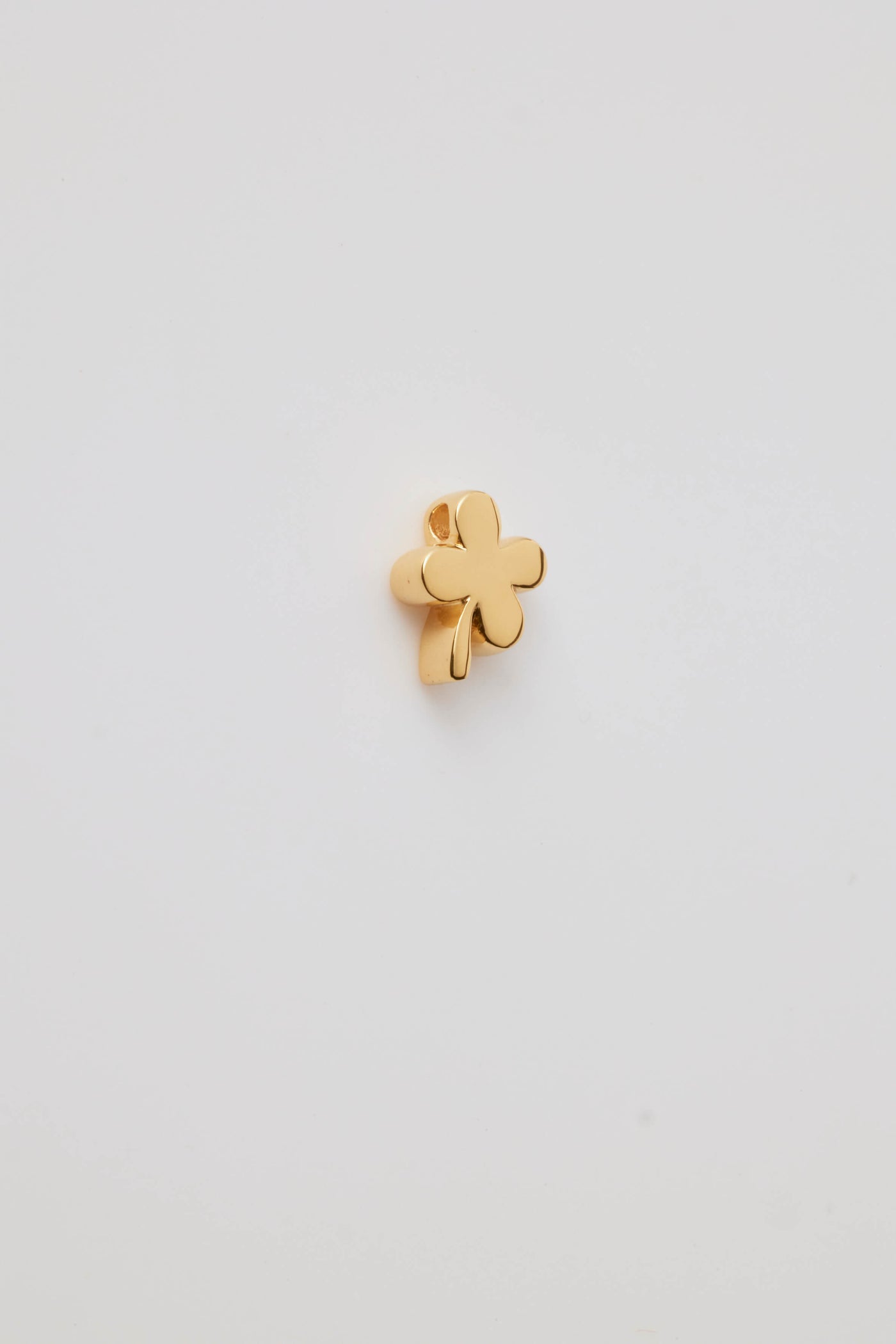 Side view of a polished gold four-leaf clover charm with smooth, rounded leaves and hole. A symbol of luck, perfect for any chain or bracelet.