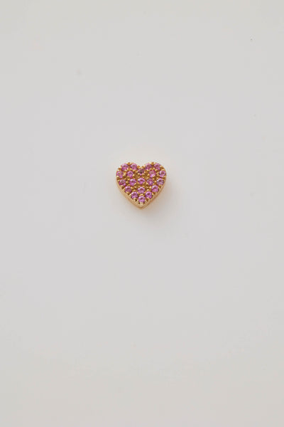 A solid gold miniature heart charm, elegantly adorned with vibrant pink sapphire gemstones. The tiny heart-shaped design is pavé-set with sparkling pink sapphires, creating a vivid, eye-catching effect. A small hole at the top allows the charm to be easily threaded through to a gold chain adding a touch of luxury and romance.