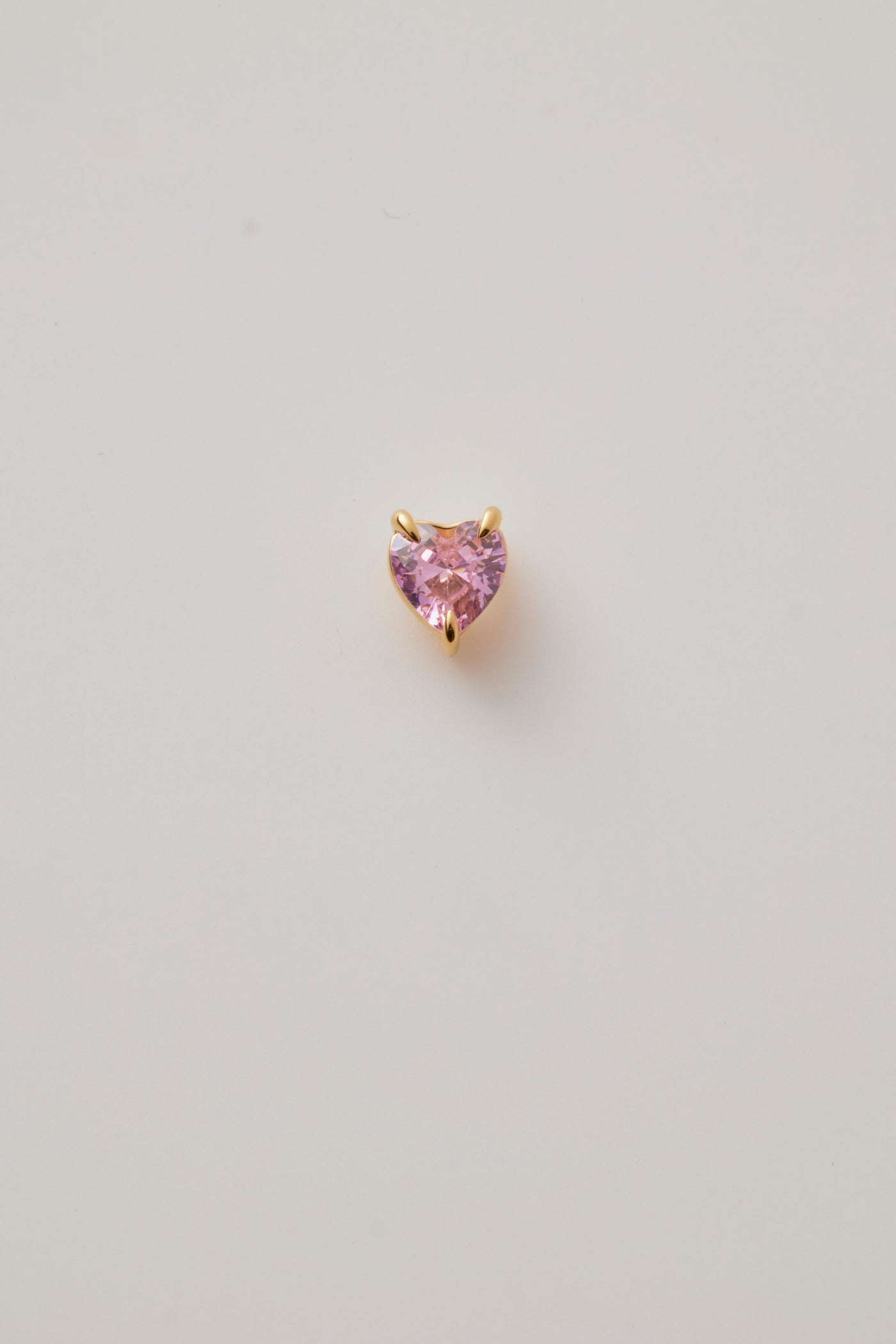 A pink faceted heart charm set in polished gold, featuring a sparkling gemstone-like finish. Elegant and perfect for any chain.