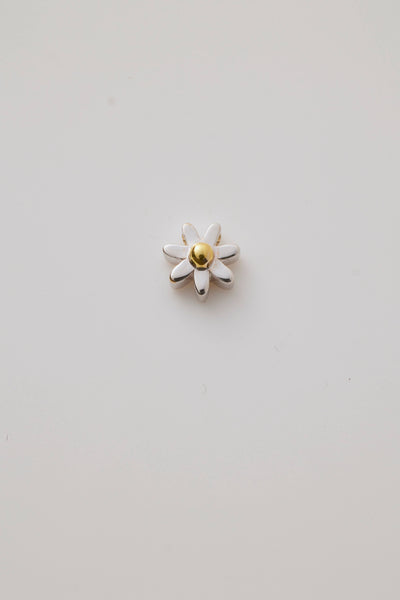 A three-dimensional daisy charm crafted in polished gold. The charm showcases delicate, detailed petals radiating from a textured centre, capturing the beauty of a blooming flower. 