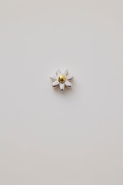 A three-dimensional daisy charm crafted in polished gold. The charm showcases delicate, detailed petals radiating from a textured centre, capturing the beauty of a blooming flower. 