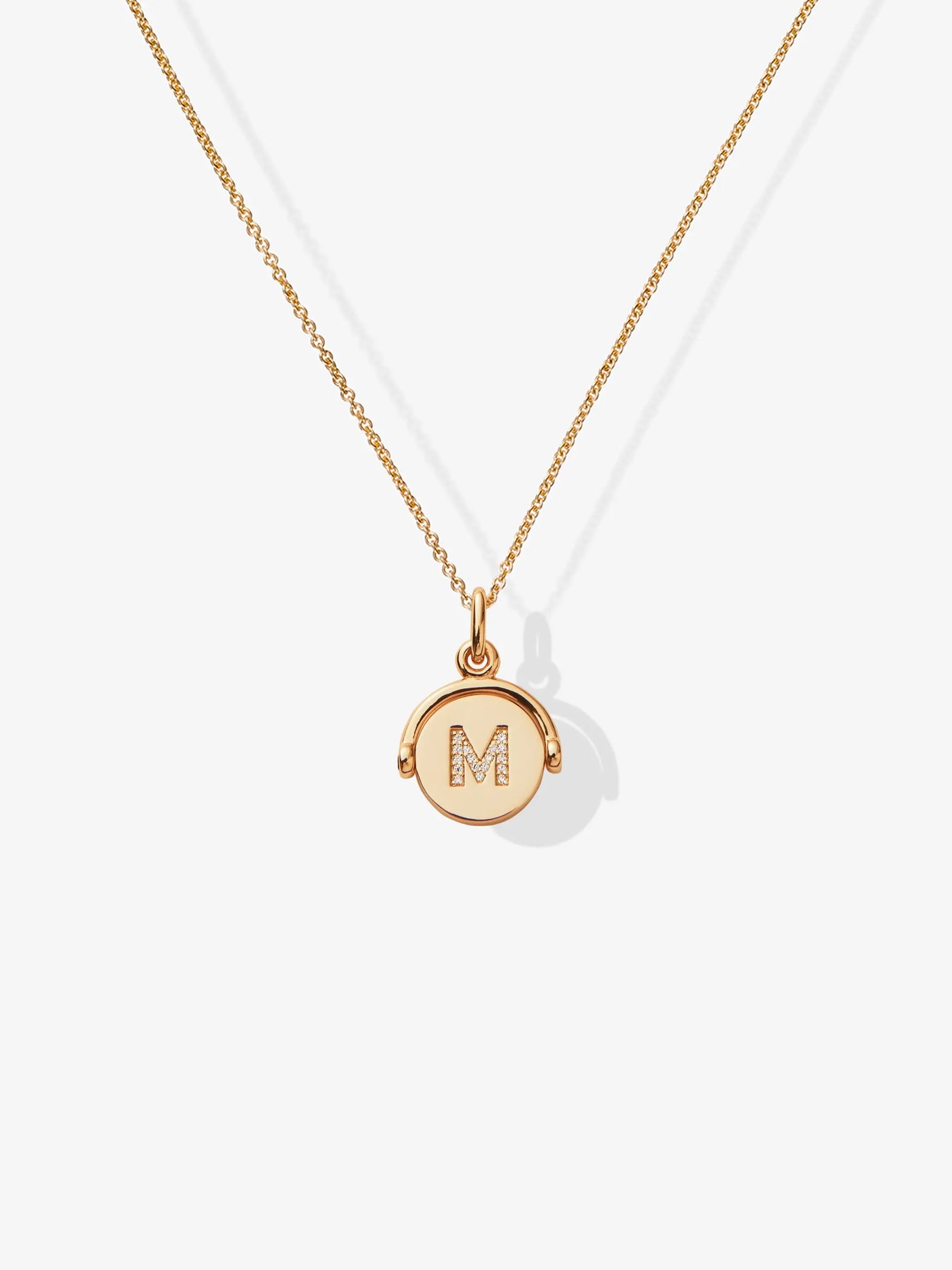 The Diamond Letter Personalised 18-Karat Gold Spinner Necklace boasts a delicate design, featuring a fine chain adorned with a small, round diamond pendant engraved with the letter "M." Tiny diamond accents add a touch of sparkle to the pendant. The thin and elegant chain perfectly complements the simplicity of this personalised jewellery piece.