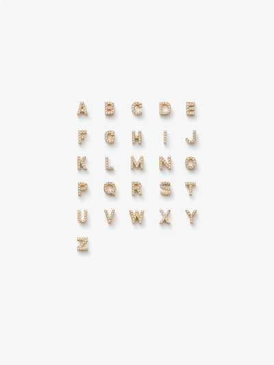 A grid of 18k solid gold and diamond alphabet letters. The letter charms set with sparkling diamonds are arranged in alphabetical order on a white background from A to Z