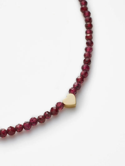 Introducing the Heart Bracelet in Garnet and 18k Gold: a delicate piece crafted with red garnet beads and accented by a small heart-shaped charm made from solid 18k gold. This simple and elegant bracelet features a gold clasp for secure fastening, making it an ideal accessory for any occasion. Custom sizes are offered to ensure the perfect fit. Photographed on a plain white background, this timeless design is sure to impress.