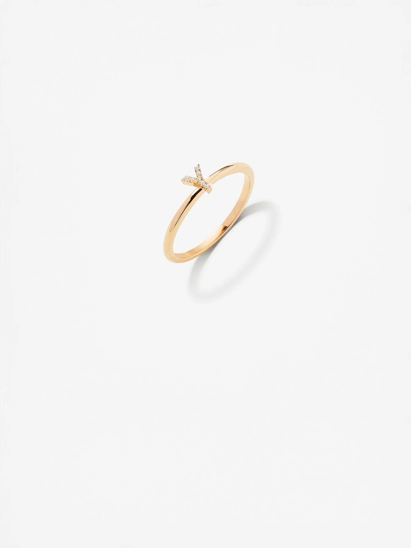 The Letter Y Ring in Diamonds and 18k Gold is an exquisite piece featuring a minimalist "Y" design at its center. Fashioned from 18k solid gold, the ring has a thin band, and the "Y" is adorned with small, round brilliant diamonds. The image is set against a white background, highlighting the ring's elegant simplicity.