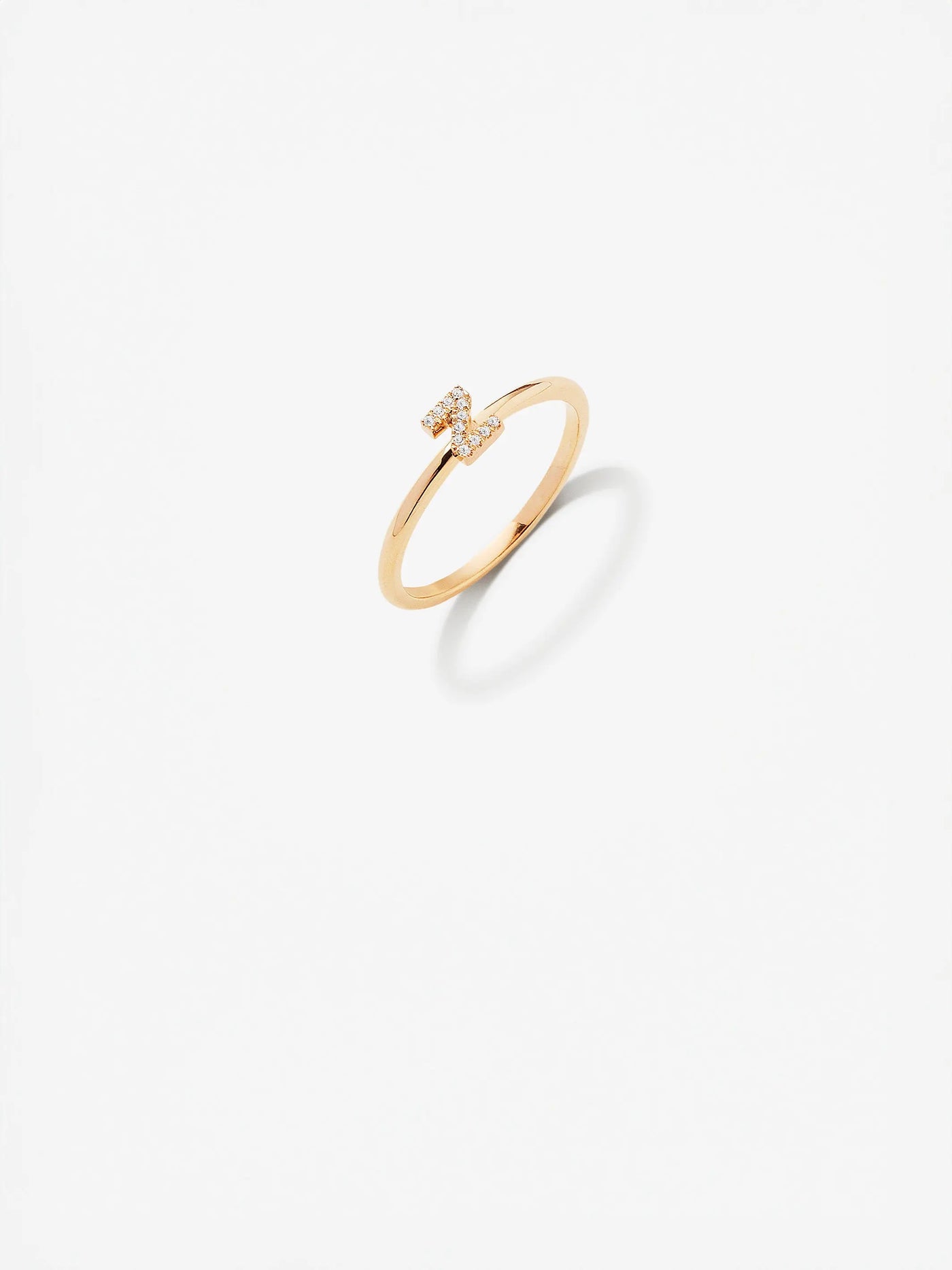 The Letter Z Ring in Diamonds and 18k Gold features a minimalist design with a delicate band crafted from 18k solid gold. At its center, a small cluster of round brilliant diamonds forms the shape of the letter "Z." This custom-made piece is set against a plain white background, creating a sleek and modern look.