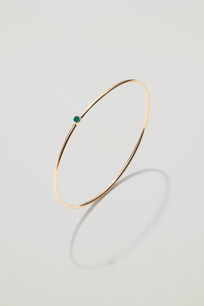 Solid gold bangle with a May emerald birthstone, symbolising growth and harmony.