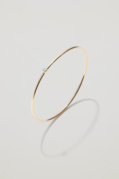 Solid gold bangle with an October opal birthstone, symbolising hope and creativity.