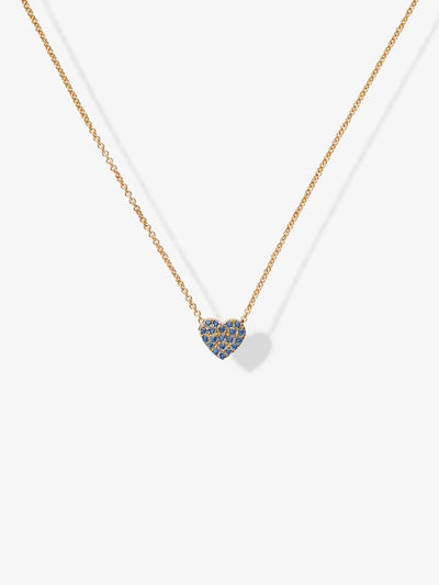 One Blue Sapphire Heart Necklace in 18k Gold featuring a small blue sapphire heart-shaped pendant adorned with gemstones, positioned at the center. The background is plain white.