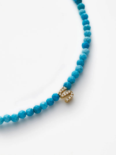 Close-up of the One Letter Bracelet in Diamonds, Turquoise, and 18k Gold, featuring a clasp adorned with small diamonds and arranged in a semi-circle against a white background.