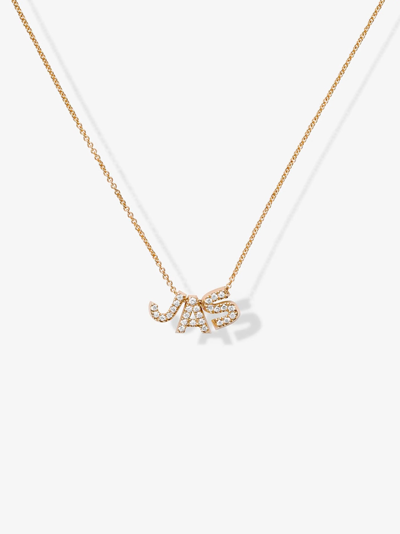 A delicate 18k solid gold necklace with a pendants "JAS" encrusted in small, sparkling diamonds. The Three Letters Necklace in Diamonds and 18k Gold is customizable and set against a plain white background.