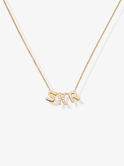 Introducing the Three Letters Necklace in Diamonds and 18k Gold: a stunning piece featuring a fine chain and three elegant letter charms. The "S" and "R" are crafted from solid 18k gold, while the "K" is encrusted with small, clear diamonds. Together, the letters spell out "SKR," evenly spaced along the chain. This exquisite necklace is beautifully showcased against a simple white background.