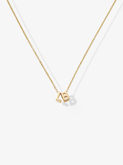 The Two Letters Necklace in 18k Gold showcases a delicate 18k solid gold chain with two gold letter charms, "L" and "B," elegantly positioned close together at the center, all set against a plain white background.