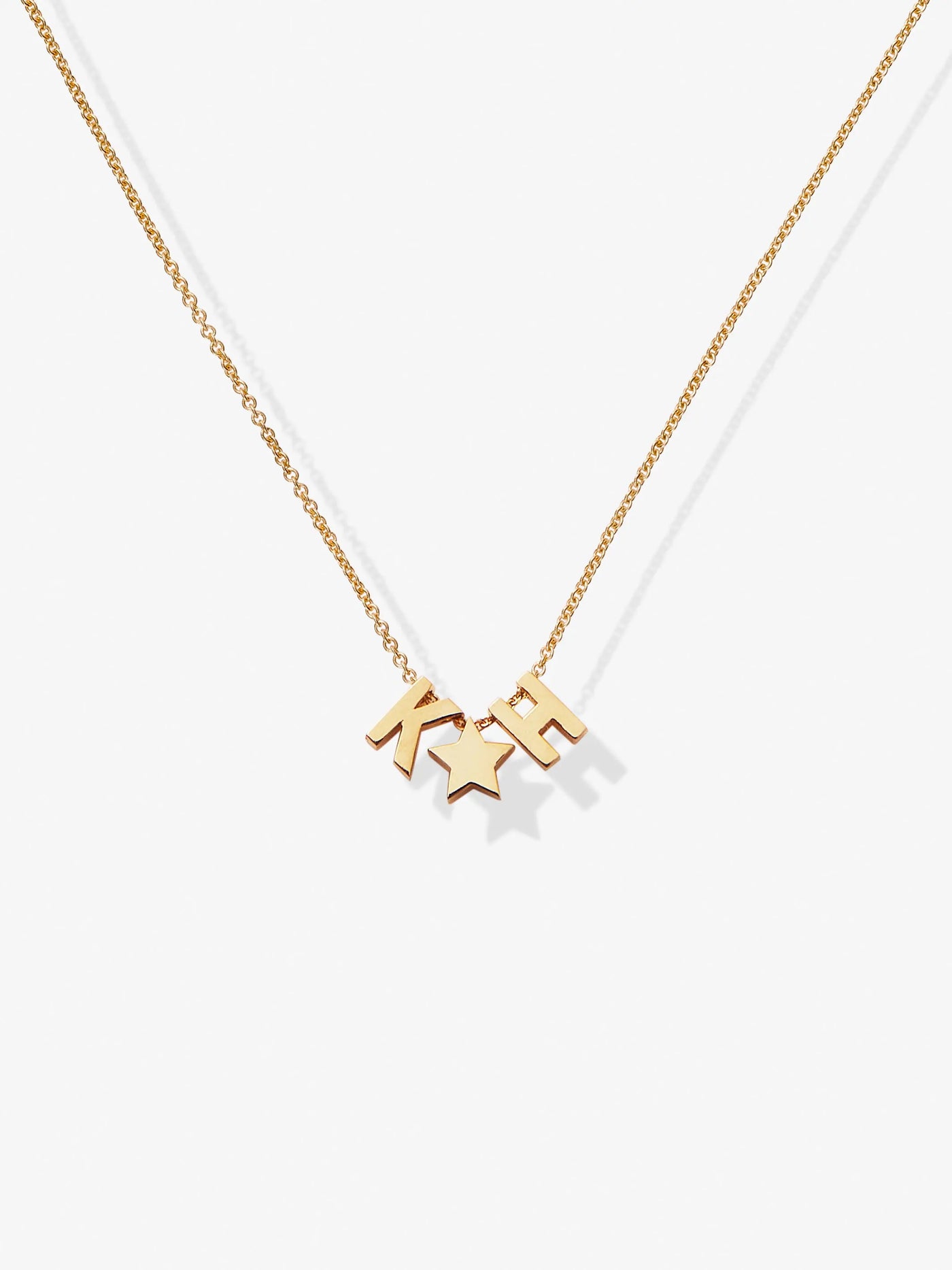 The Two Letters and Star Necklace in 18k Gold is a delicate piece featuring three charms: the letters separated by a small star, all suspended from a fine chain with an openable connector clasp. The plain white background highlights the simplicity and elegance of this exquisite necklace.