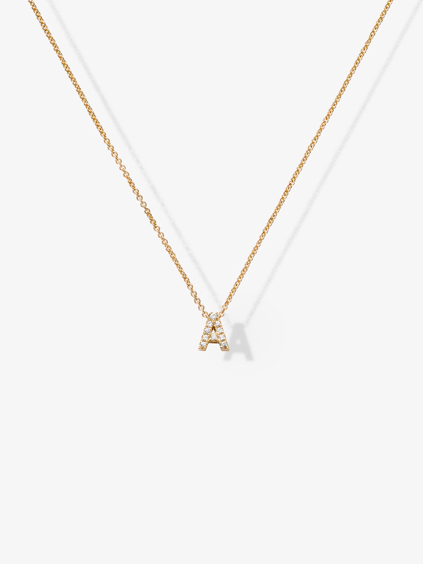  A delicate 18k solid gold necklace featuring two small, capital letter charms encrusted with diamonds. This stunning Two Letters Necklace in Diamonds and 18k Gold is displayed against a plain white background.