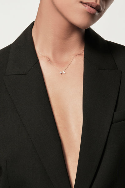 Close-up of a woman wearing a minimalist 18k gold initialS “A”  diamond star charm necklace , styled with a black blazer – personalised alphabet pendant jewellery