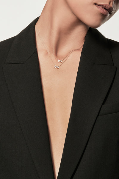 A delicate 18k solid gold necklace featuring two small, capital letter charms encrusted with diamonds. This stunning Two Letters Necklace in Diamonds and 18k Gold is displayed against a plain white background.