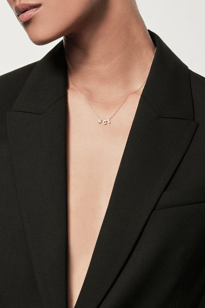 Close-up of a woman wearing a minimalist 18k gold initialS “G” "F" diamond star charm necklace , styled with a black blazer – personalised alphabet pendant jewellery