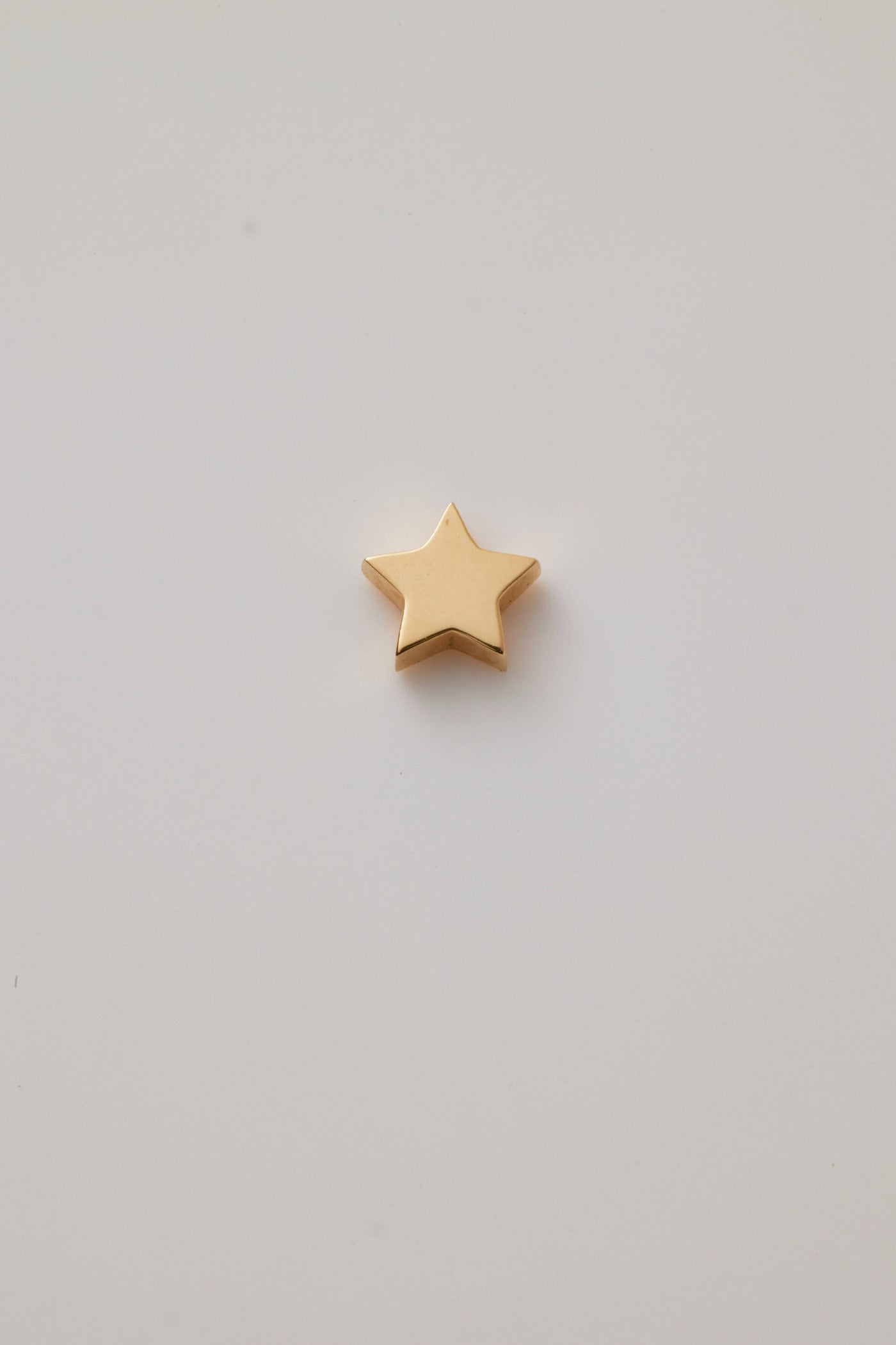 Polished solid gold star charm, a symbol of remembrance and love.