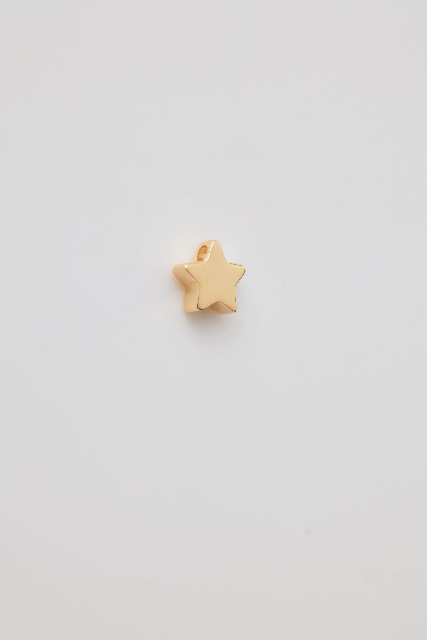 Polished solid gold star charm, a symbol of remembrance and love.