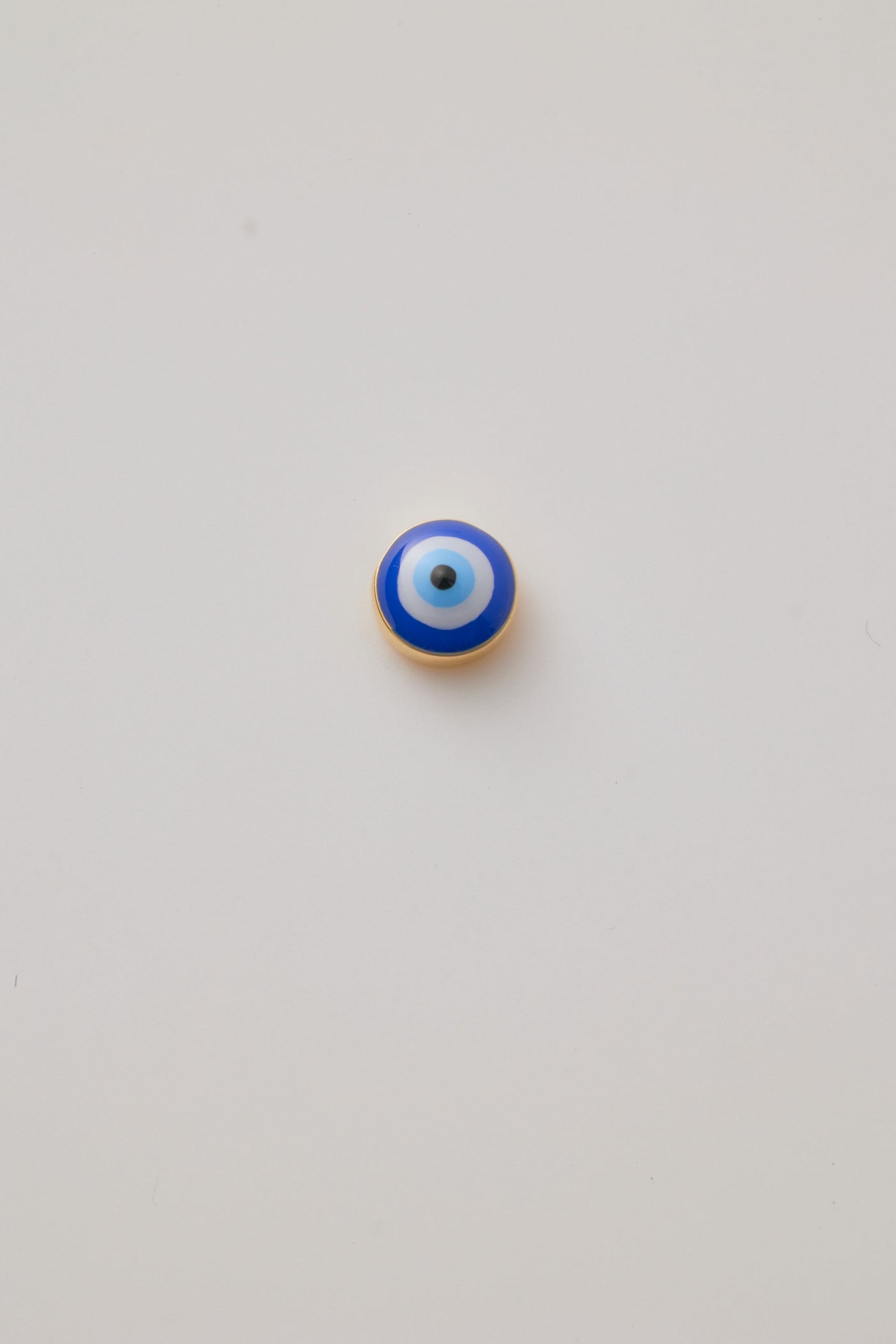 Small solid gold evil eye charm, designed to slide onto a necklace chain for a personalised jewellery piece.