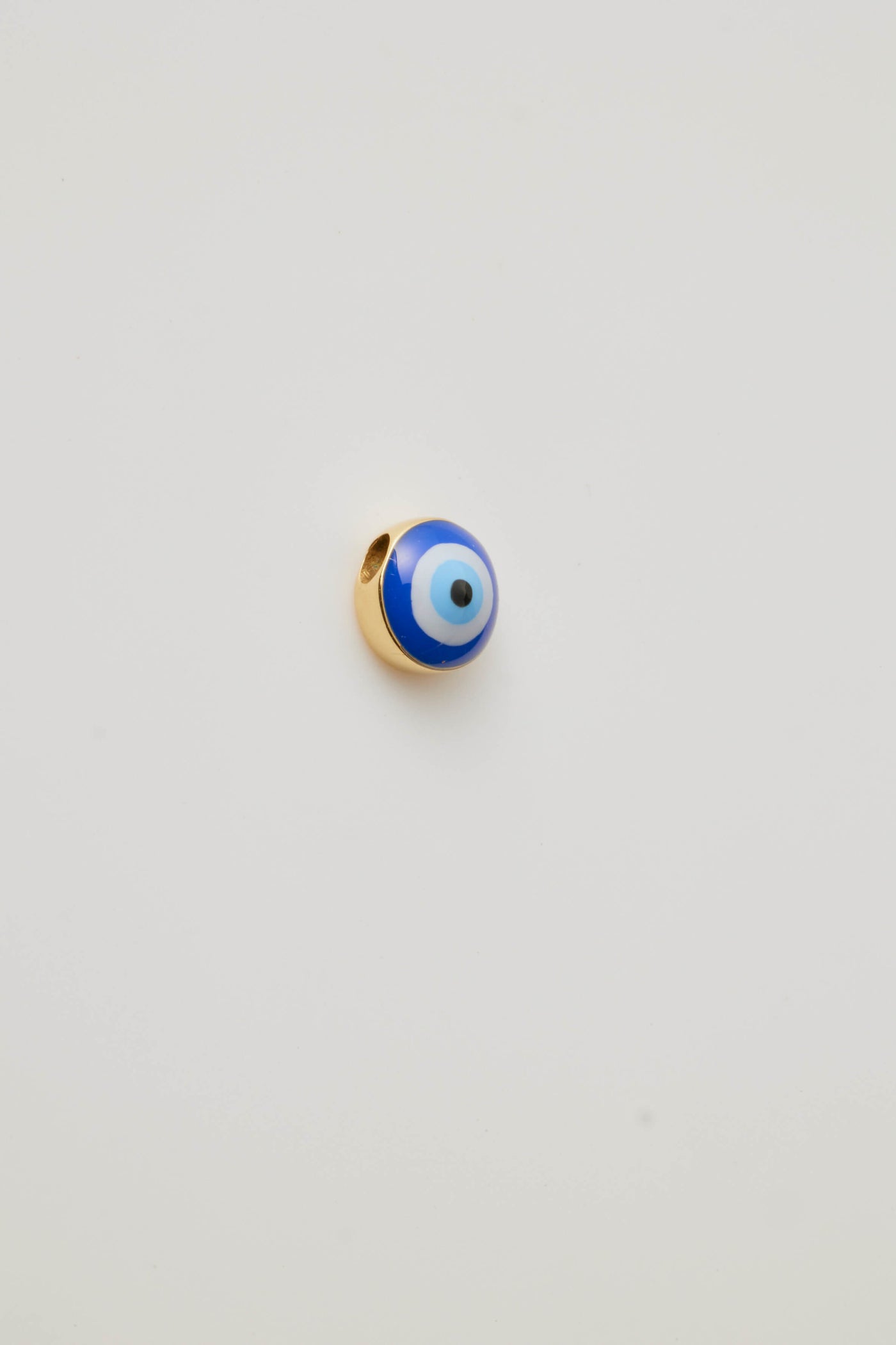 Small solid gold evil eye charm, designed to slide onto a necklace chain for a personalised jewellery piece.