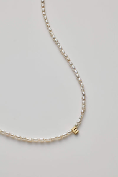 14K gold necklace with lustrous pearl and a gold letter charm.